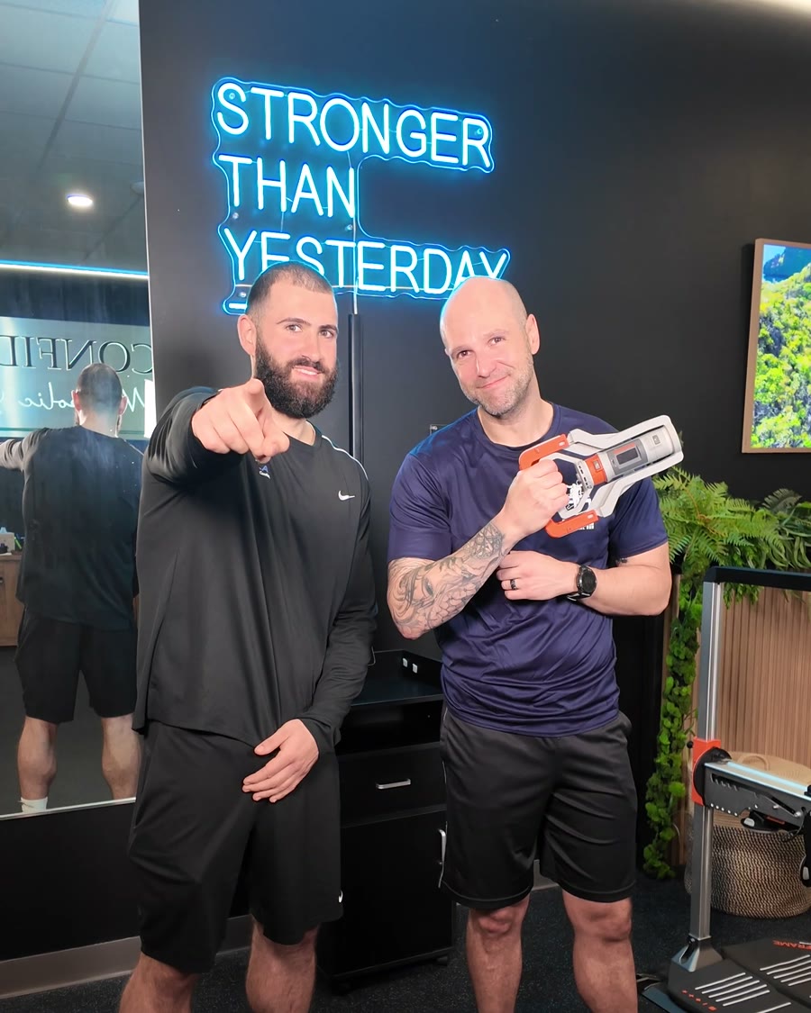 Brian Barao holding the grip strength tester at MetaLab, with Ryan from the MetaLab team